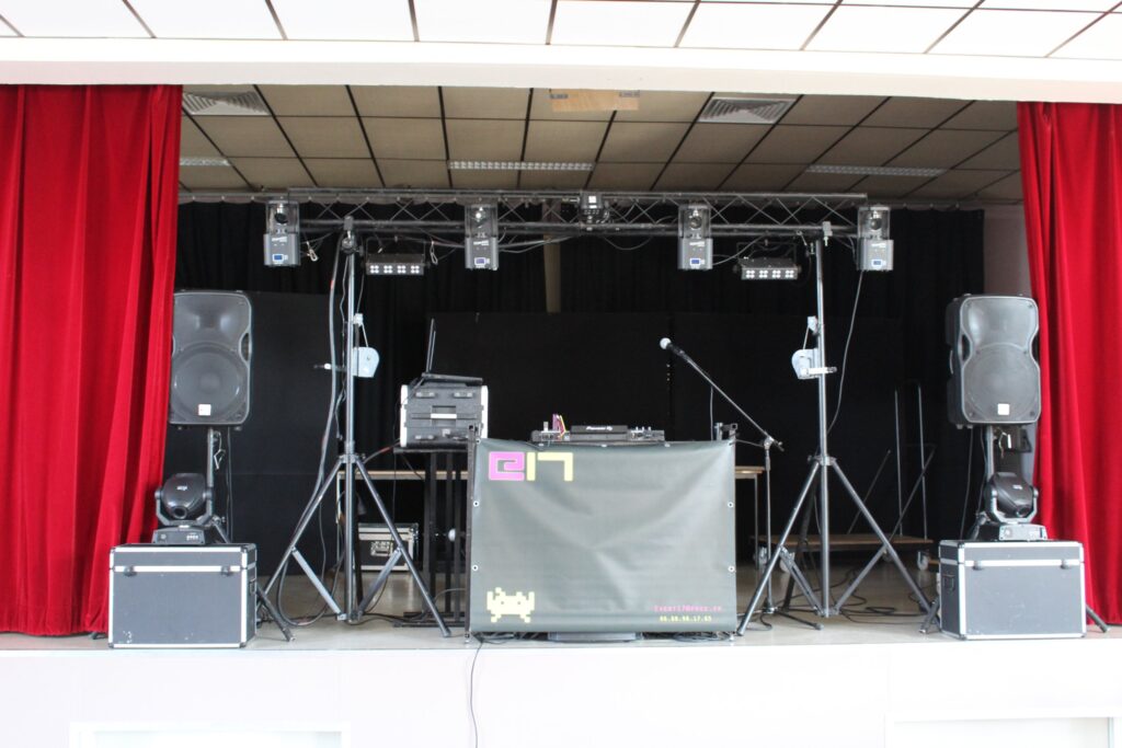 Installation complète event17 sur scène : enceintes, lyres et jeux de lumières sur portique, stand DJ