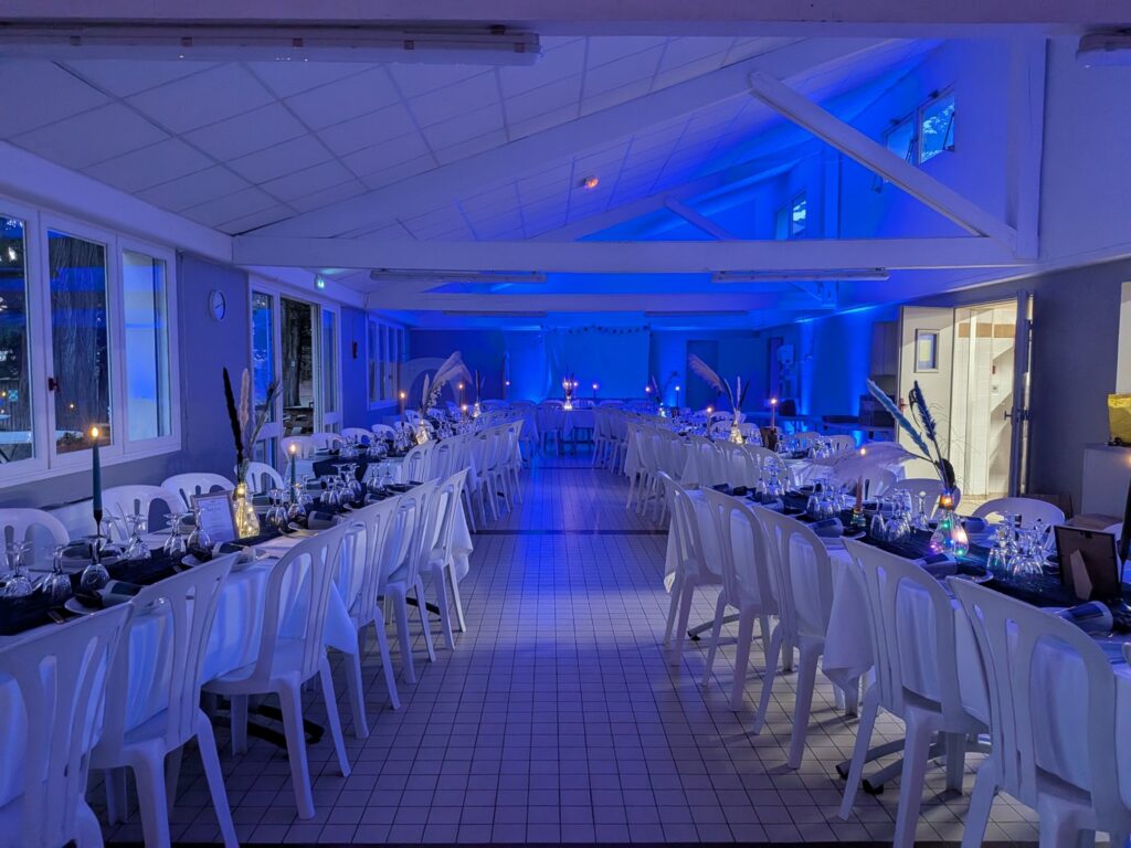 Salle de réception mise en valeur par un éclairage d'ambiance bleu, tables dressées